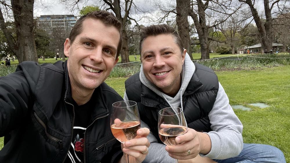 Two men holding wine glasses in a park